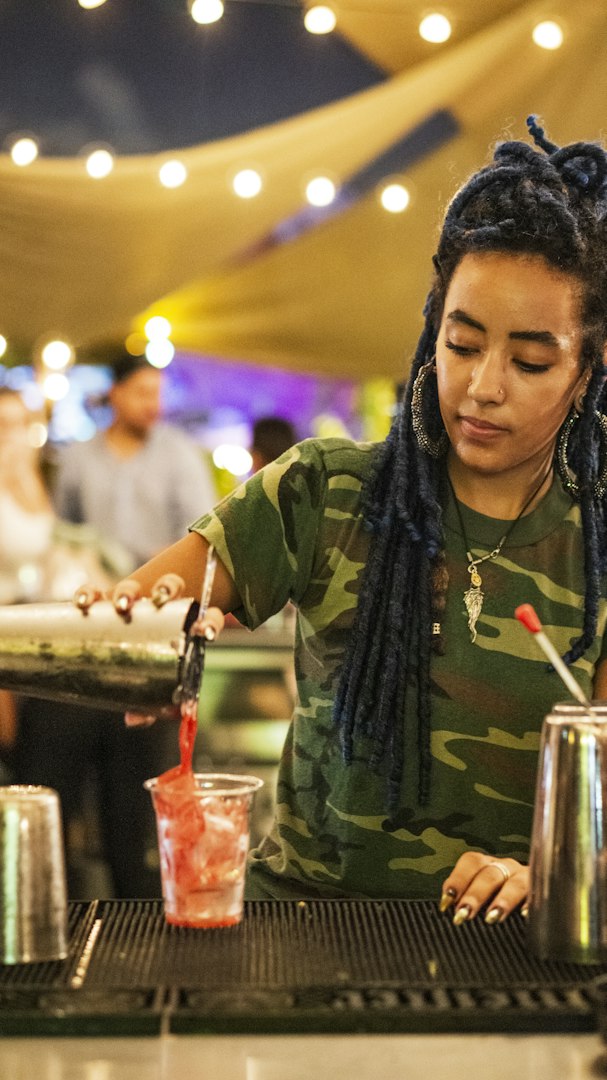 Bartender pouring alcohol on a cocktail in a night club bar. Close-up